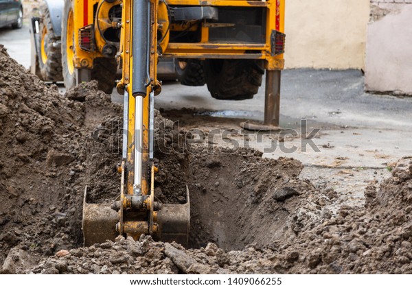 Excavator digs a trench. Repair work in the\
courtyard of a residential\
building.