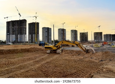 Bagger, der Erdarbeiten während des Baus einer Straße in einem neuen Wohngebiet in der Stadt. Turmkräne sind große, mehrstöckige Betongebäude. Konzept der Bauindustrie