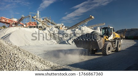 Excavator front end loader works against the background of equipment at a mining plant, panorama. Mining industry.