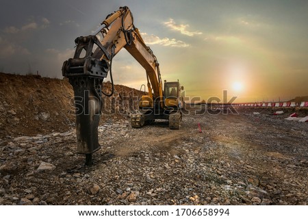 Excavator with hydraulic hammer on road construction works