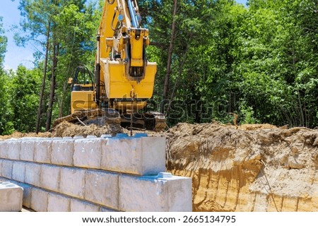 Excavator is lifting blocks during construct retaining wall newly at construction site.