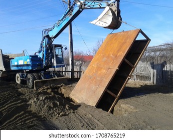 Excavator Lifting A Trench Shoring Box. Sewerage System Construction