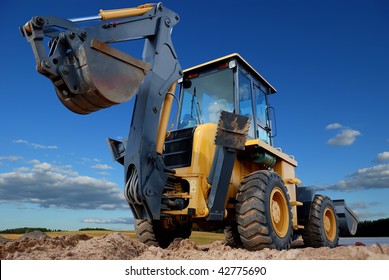 Excavator Loader with raised backhoe standing over cloudscape sky