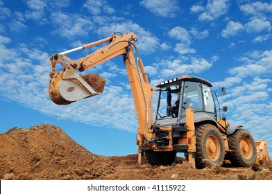 Excavator Loader with rised backhoe standing in sandpit with over cloudscape sky