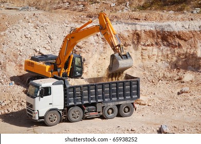 Excavator Loading Dumper Truck With Sand At Construction Site