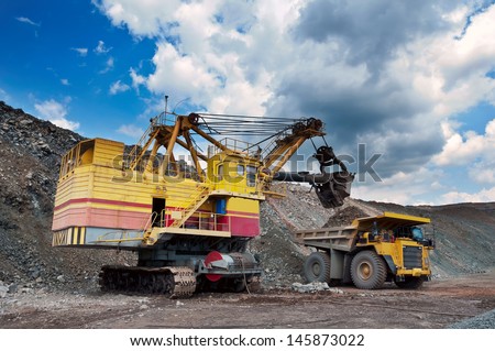 Excavator loading iron ore into the heavy dump truck on the iron ore opencast mining
