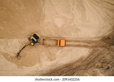 Excavator loading sand into a truck body in Sand quarry, industrial extraction of sand for construction industry