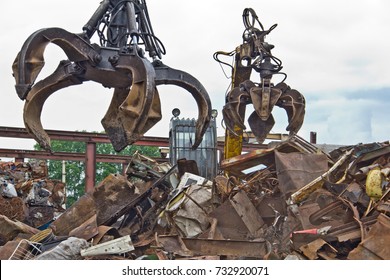 Excavator Is Loading Scrap Metal Junk Into A Bin At A Garbage Dump Or Recycling Center.