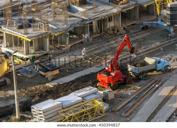 Excavator loads the ground in the car at the\
construction site.