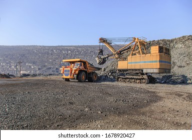 Excavator loads iron ore into a large dump truck