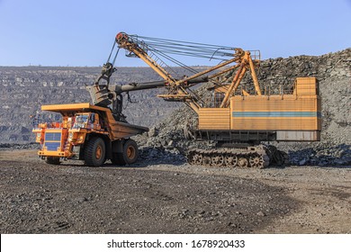 Excavator loads iron ore into a large dump truck