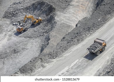 Excavator loads ore into a large mining dump truck. Open pit. Top view