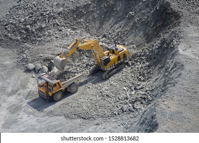 Excavator loads ore into a large mining dump truck. Top view. Open pit.