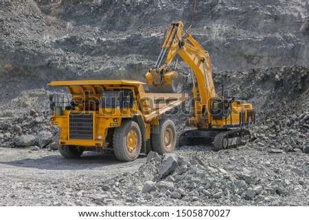 Excavator loads ore into a large mining dump truck. Open pit