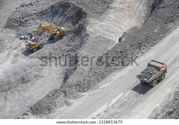 Excavator loads ore into a large mining dump truck.\
Open pit. Top view