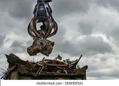 An excavator loads scrap metal into the back of a truck at a landfill or recycling center. - Powered by Shutterstock