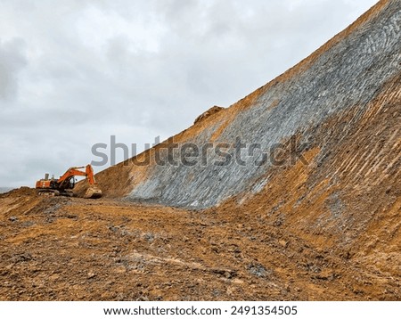 Excavator machine profiling slopes and bench in open pit mine.
