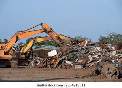 Excavator magnet lifting steel scraps from recycling materials pile at scrap yard in recycling factory. Excavator with electro and magnetic sucker magnet chuck. Special excavator. Scrap metal magnet. - Powered by Shutterstock