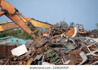 Excavator magnet lifting steel scraps from recycling materials pile at scrap yard in recycling factory. Excavator with electro and magnetic sucker magnet chuck. Special excavator. Scrap metal magnet. - Powered by Shutterstock