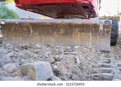 Excavator On A Construction Site Photographed From Behind At Ground Level. Dozer Blade Is Visible. Space For Text.                               