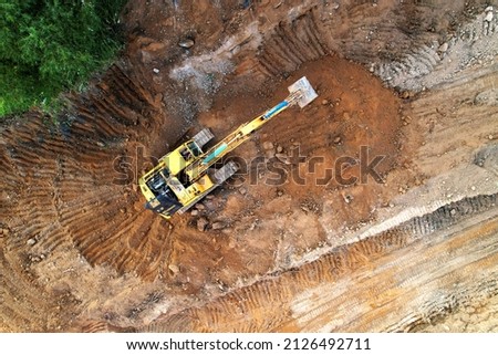 Excavator on earthmoving at construction site. Excavator on earthworks. Open pit development and sand mining. Loader digg ground, top view. Earthmover and digger on groundwork.
