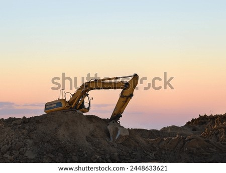Excavator on earthmoving on sunset. Open-pit mining. Backhoe dig ground in quarry. Heavy construction equipment on excavation on construction. Excavator on groundwork foundation. Road construction.