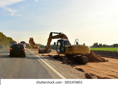 Excavator On Earthworks And Road Construction In City. Temporary Traffic Regulation From Carrying Out Road Works Or Activity On The Public Highway. Roadway Work Zone Safety. Out Of Focus, Motion Blur