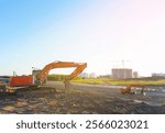 Excavator on groundwork on Construction site. Backhoe dig foundation for house construction. Building renovation. Excavator on earthworks for road construction. Tower cranes on buildings construction.