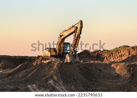 Excavator in open pit mining. Excavator on earthmoving on sunset. Loader on excavation. Earth-Moving Heavy Equipment. Earth mover ar construction site. Backhoe Loader on dig foundation.  