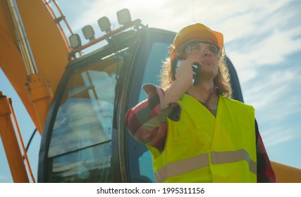 Excavator Operator In Hard Hat Talking By Smartphone.