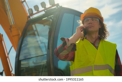 Excavator Operator In Hard Hat Talking By Smartphone.