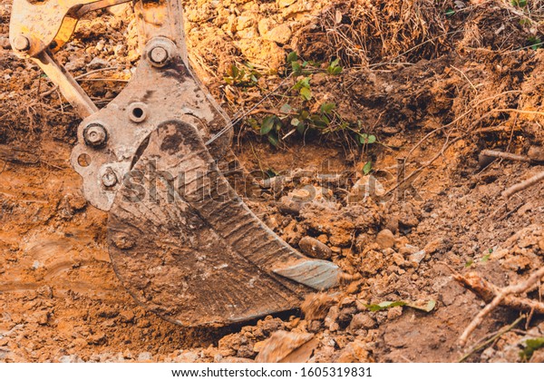 The excavator performs excavation\
work by digging the ground with a bucket in the\
forest.