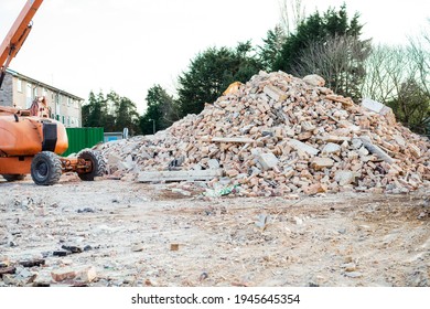 Excavator Removes Construction Waste After Building Demolition. Building Rubble, Bricks, Stones. Junk, Garbage Piled Up. Street Scene. Recycling Industry, Rubbish Removal, And Collection Service