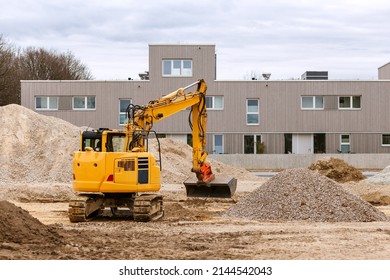 Excavator Spreads Rubble And Soil On Construction Site. Landscaping After Construction Public Building