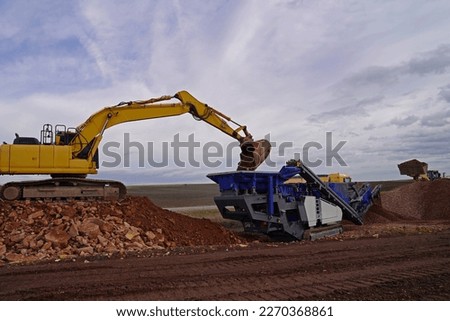 excavator, stone crusher, truck and wheel loader in use for red rock demolition materialcrushing and removal of fill material 