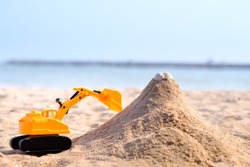 Excavator Toys With Sand Castle Have Rock Ontop On  The Beach With Blue Sea And Sky Backgound.