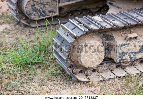 Excavator tracks.\
Old iron caterpillars of the bulldozer of the tractor on the road.\
bulldozer caterpillar tracks. Black caterpillar tractor grader with\
the wheels on the\
ground.