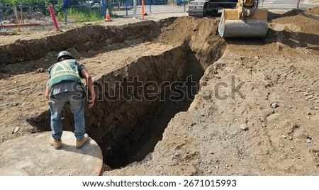 Excavator trims trench alignment while crew inspects grade during sanitary sewer installation.