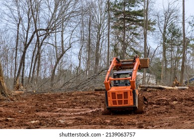 Excavator Uprooting Trees On Land In Bulldozer Clearing Land From Trees, Roots And Branches With Dirt And Trash