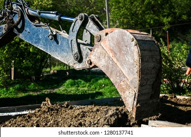 Excavator used for pipe laying works and house foundation. Digging a trench using a dump truck. Pipeline earthworks at the construction site. Digger backhoe filled with earth.   