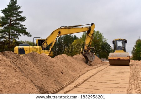 Excavator and Vibro Roller Soil Compactor at road construction and bridge projects in forest area. Heavy machinery for road work. Building a road works. Leveling and compaction of ground