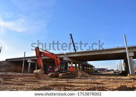 Excavator working at construction highway ramps and bridgeworks. Roundabout and traffic bridge construction. Road work on traffic highway, road intersection junction and freeway. Bridge project works Stock foto © 