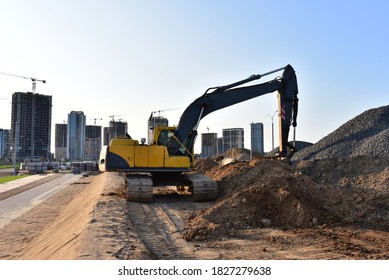 Excavator working at construction site. Backhoe on road work and earthworks. Earth-Moving Heavy Equipment for construction jobs, home building to large-scale commercial and civil projects.