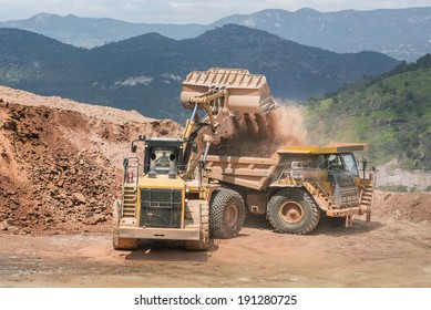 Excavator Working With Dump Truck Mining Trucks Working Side By Side To Uncover Precious Metals In An Open Mine 