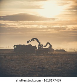 Excavator Working On Construction Site, Loading A Dump Track At Sunrise.