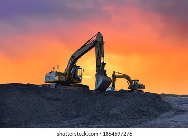 Excavator working on earthmoving at open pit mining on amazing sunset background. Backhoe digs sand and gravel in quarry. Heavy construction equipment during excavation at construction site - Shutterstock ID 1864597276