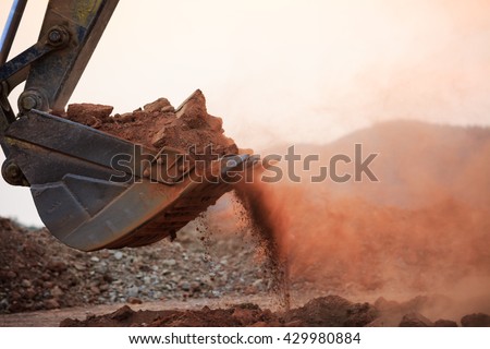 Excavator working with red soil and dusty