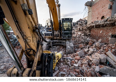 Excavatoron destructed buidling ruins. Closeup view to demolishing machine.