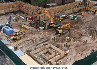 Excavators digging on skyscraper construction site with foundation pit