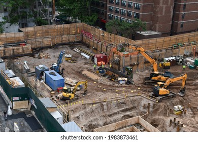 Excavators digging on skyscraper construction site with foundation pit